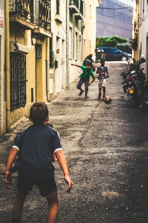 boys playing soccer in street