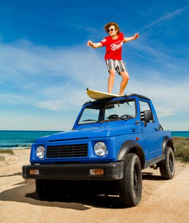 Guy on surfboard on roof of car