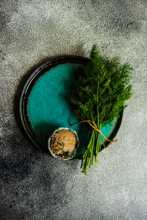 Blue plate with fresh dill on a grey counter