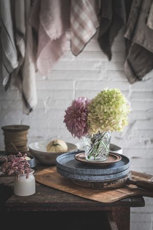 Table with flowers in vase on trays near towels hanging on thread