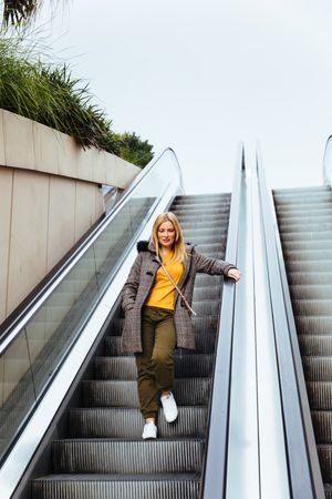 Blonde woman going down escalators