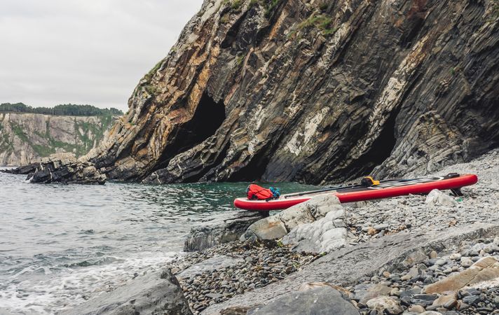 Paddle board on rocky shore near water