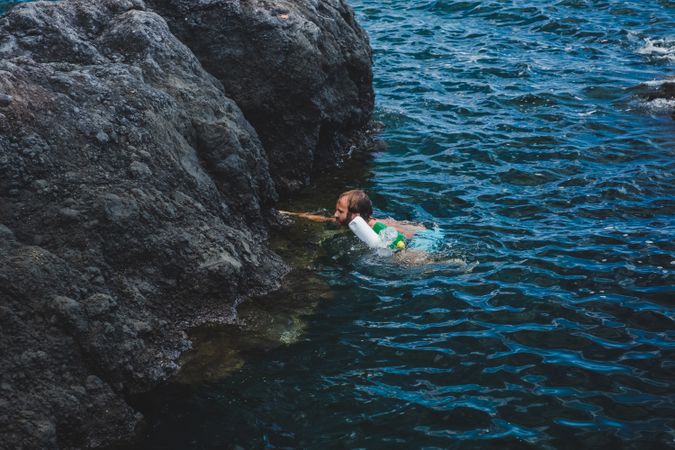 Man swimming in water with rubbish