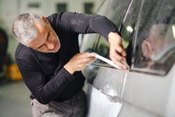 Mechanic putting protective tape on car