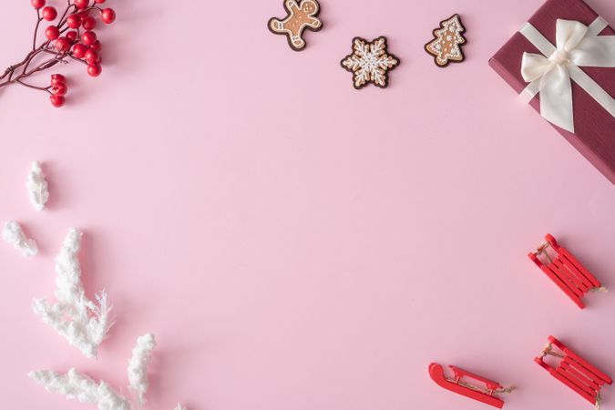 Winter Christmas table layout with presents, decorations, branches on pastel pink background