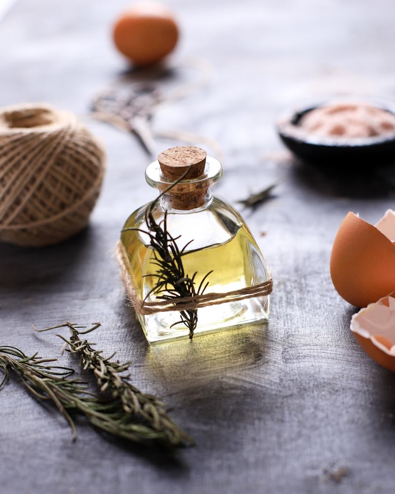 Small Bottle of Olive Oil with herbs above Rustic Table. Ready to Cook