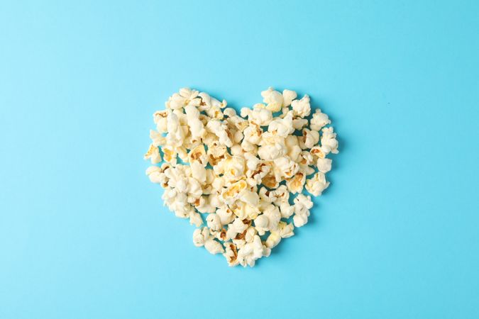 Flat lay composition with popcorn heart on blue background, space for text