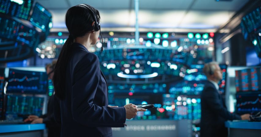 Portrait of a Young Stock Exchange Broker Using Tablet Computer, Researching Real-Time Stocks Data, Analyzing Commodities and Exchange Market Charts. Professional Investment Banker in Office