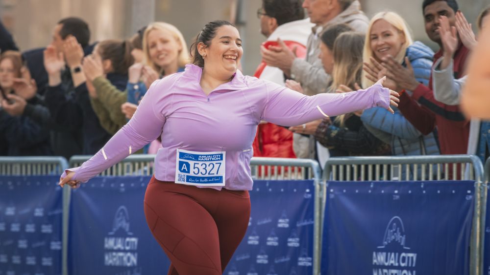 Portrait of a Smiling Female Runner Crossing the Finish Line and Demonstrating her Willpower.