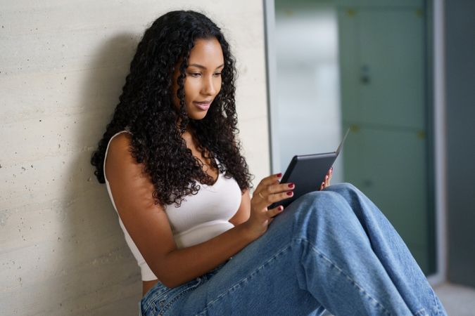 A Young Woman Engaged in Using a Tablet in a Relaxed and Cozy Indoor Setting Today