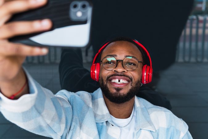 Cheerful Black man in headphones taking selfie
