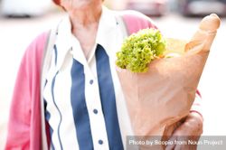 Older woman in pink cardigan holding grocery bag standing in close-up 5639z4