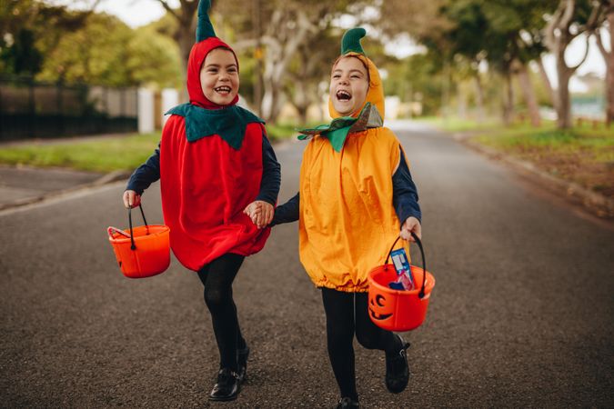 Happy kids in halloween costume trick or treating outdoors