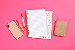Stationery and smartphone on pink background, space for text