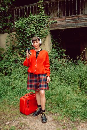 Woman in headphones with suitcase choosing music