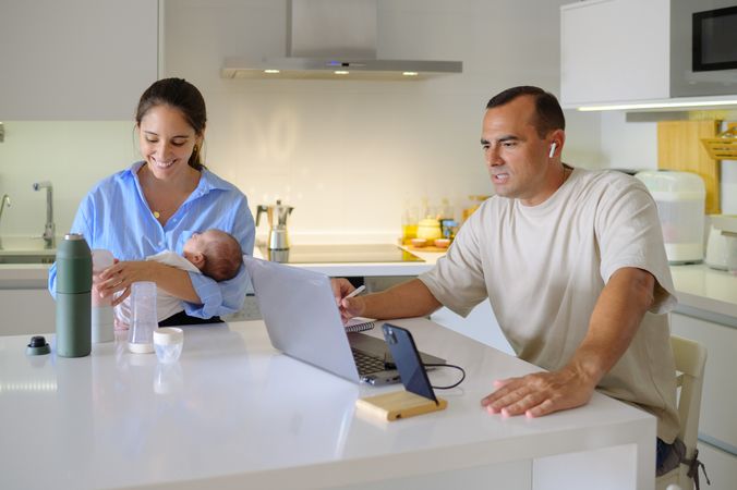 A man and woman holding a baby in front of a laptop