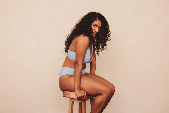 Woman sitting on stool in blue underwear in studio