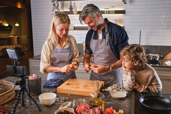 Parents peeling potatoes near son