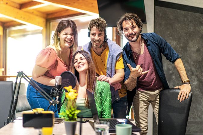 A cheerful group of podcast hosts engaging in a lively recording session at a studio