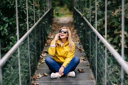 Happy female traveler talking phone on suspension bridge in summer