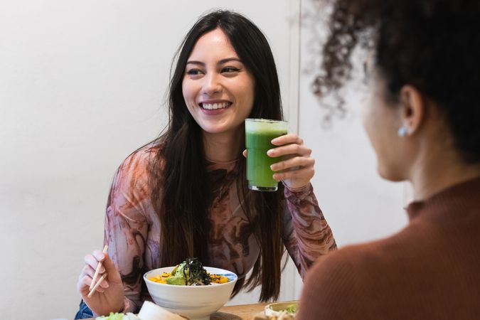 Cheerful diverse women drinking smoothie in restaurant