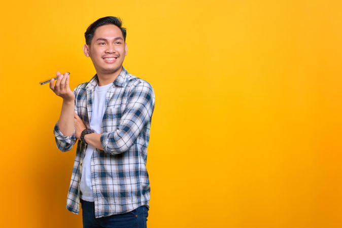 Asian male smiling while using speaker phone in studio shoot with copy space