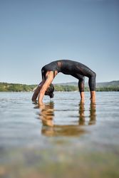 Woman doing yoga wheel pose outside at lake