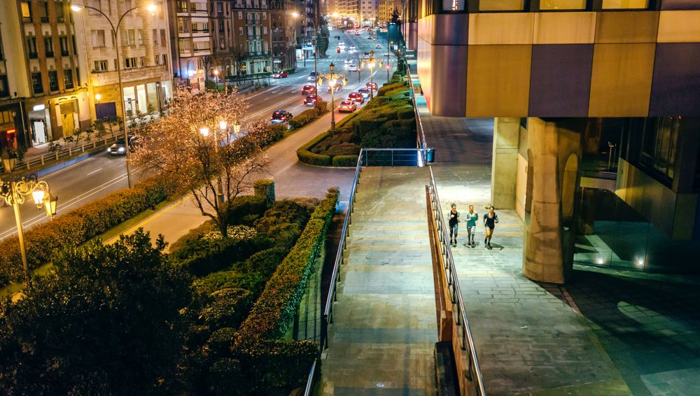 Looking down female friends running together over city runway at night