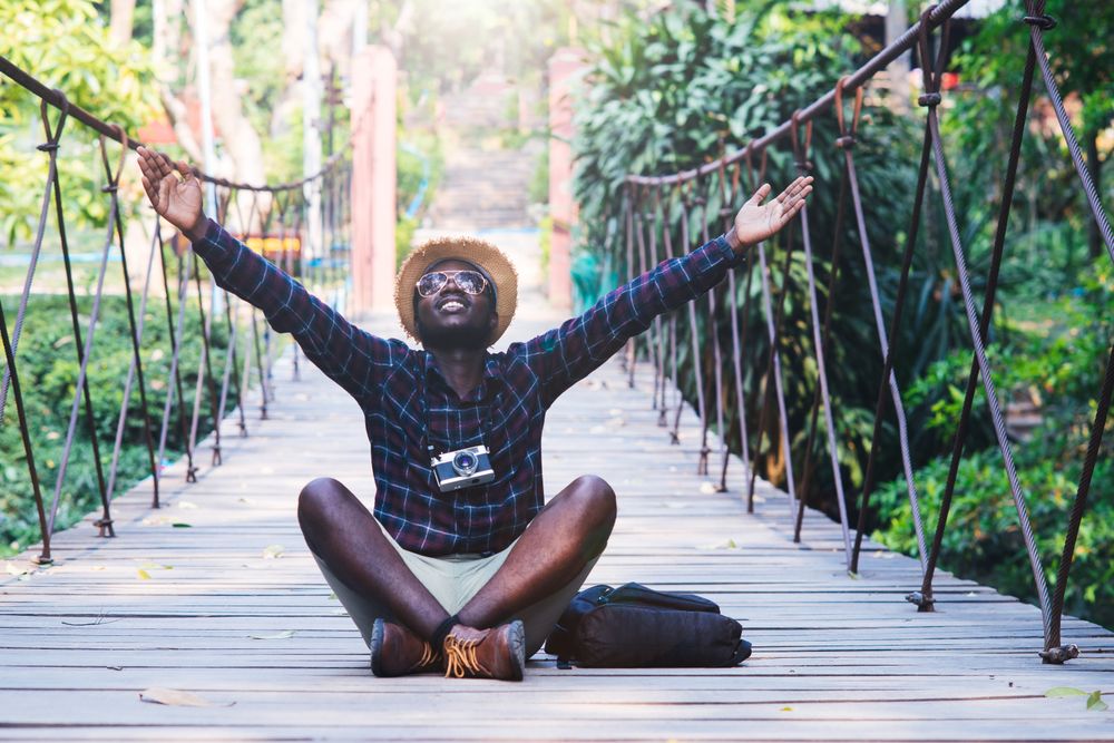 Man sitting on wooden footbridge raising his arms
