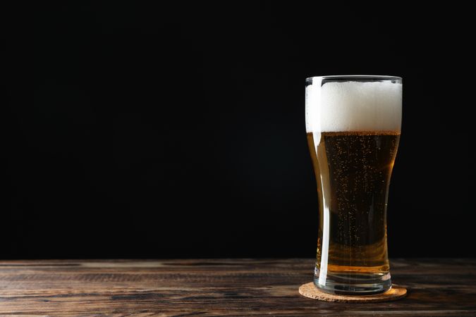 Mug with beer on wooden table, space for text