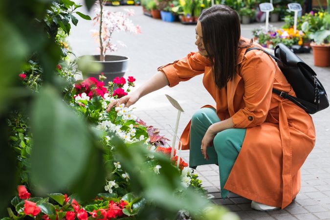 Cheerful woman choosing flowers in garden center