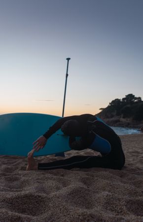 Man practicing paddle surfing with neoprene in a sunrise