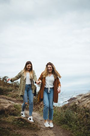 Happy female friends walking on trail at seaside