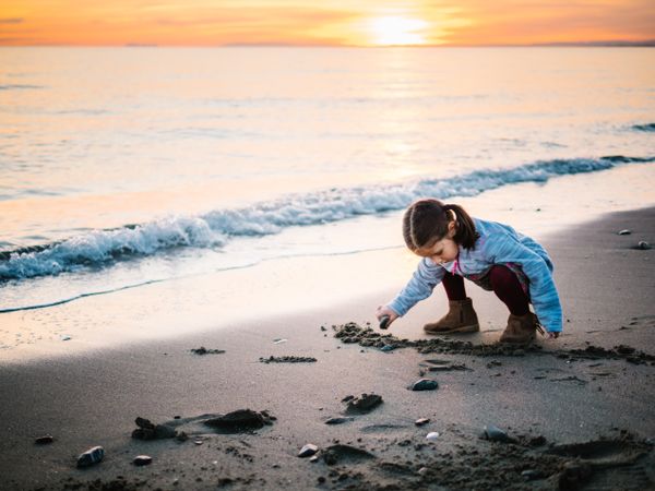 Cute little girl playing with sand at beach
