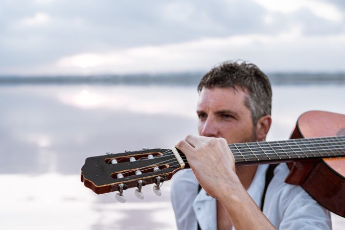 Musician with guitar on pink sandy water