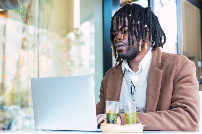 Black man browsing on laptop on restaurant terrace