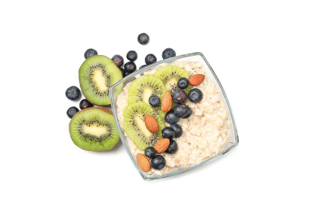 Bowl with oatmeal porridge and fruits isolated on plain background
