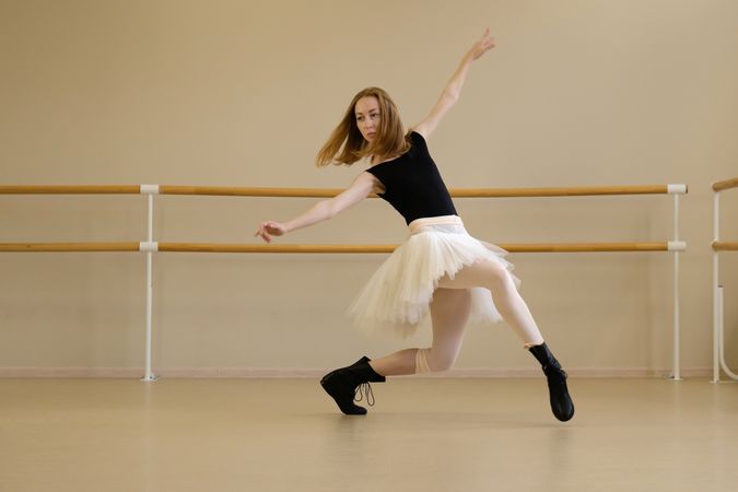 Ballerina in shoes and tutu, mid-movement with arms extended
