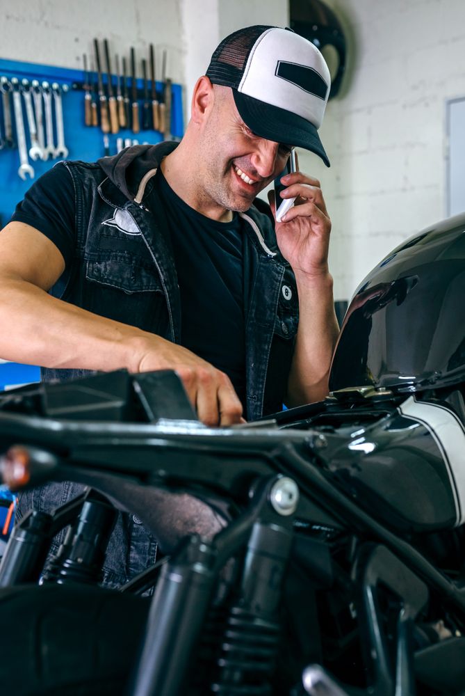 Mechanic talking phone while fixing motorbike