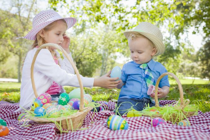 Cute Young Brother and Sister Enjoying Their Easter Eggs Outside