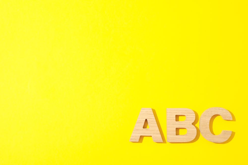 Wooden letters of English alphabet on color background, space for text