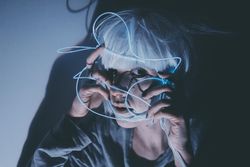 Portrait of woman with light hair holding blue led light thread to her face