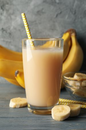 Bananas and juice against gray background. Fresh fruit