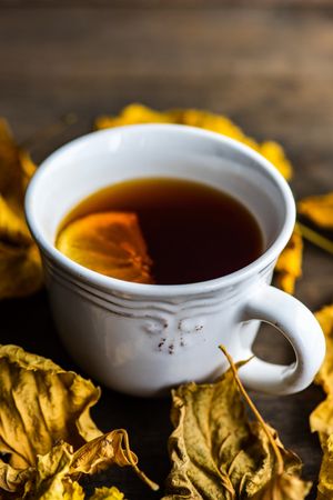 Cup of tea with slice of lemon and dried leaves
