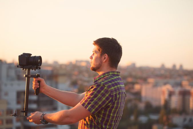 Male taking video of himself on roof at sunset