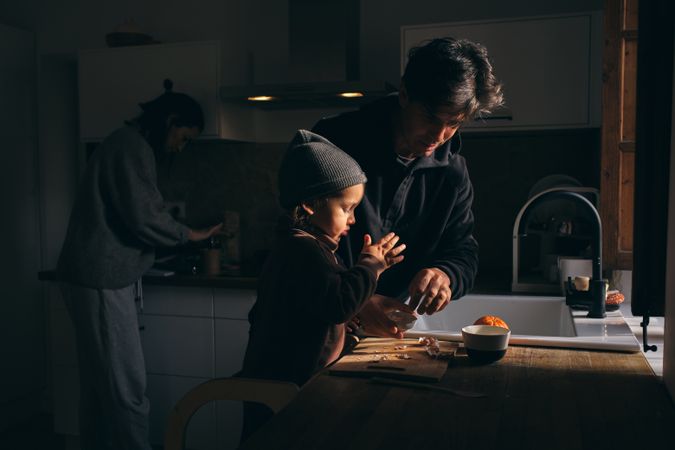 Young family with adorable child preparing dinner together in ki