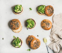 Fresh vegan burgers on seeded buns arranged on light background