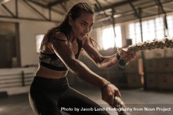 Fitness woman using battle ropes for exercising 5Q23ZE