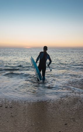 Man practicing paddle surfing with neoprene in a sunrise