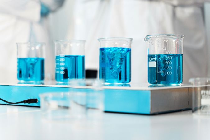 Beakers filled with blue liquid on a laboratory bench, highlighting scientific measurement and analysis